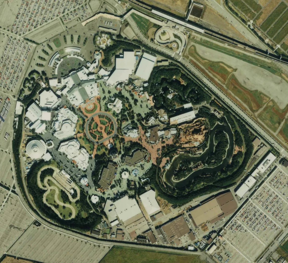 Aerial photograph of Tokyo Disneyland in 1989: a circular plaza near the center of the park, with paths branching out from it toward the surrounding lands.