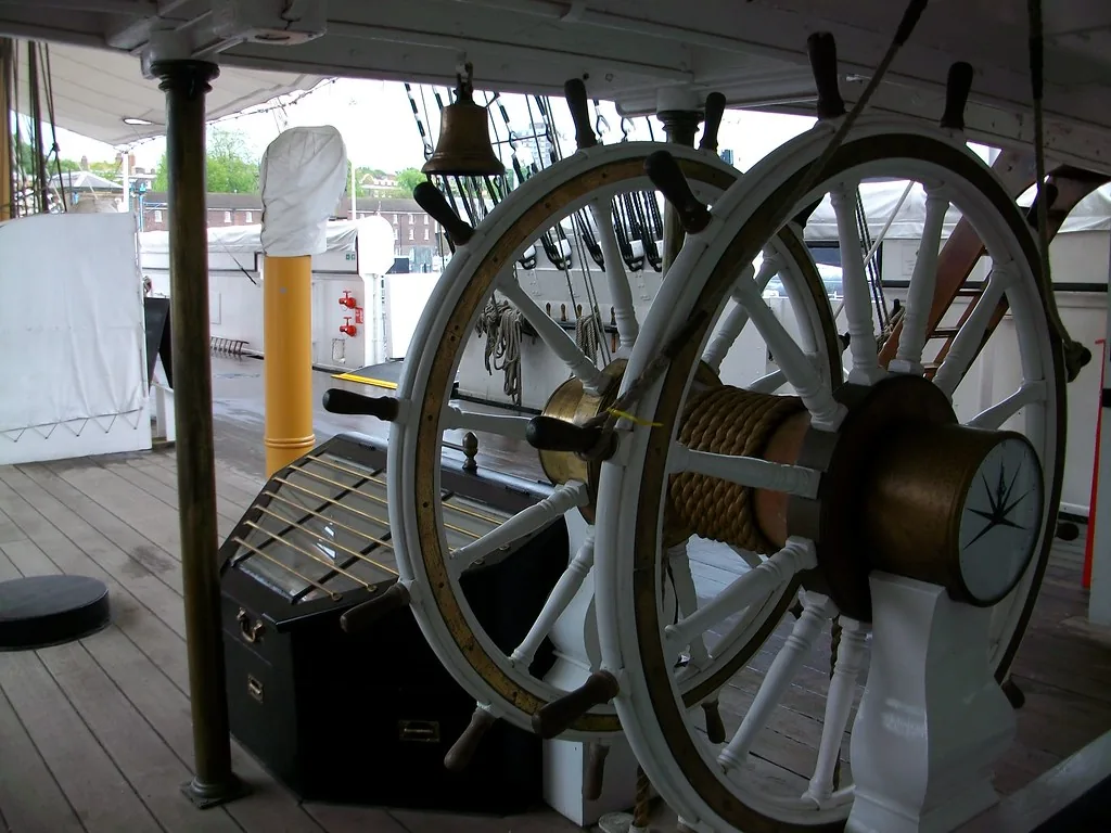 The double steering wheel of a sailing ship on deck, with a compass rose mounted at its center